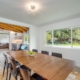 A well-lit dining room showcasing a wooden table surrounded by chairs, creating an inviting space for meals and gatherings.