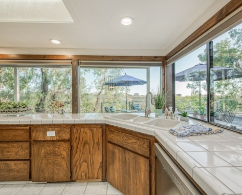 A kitchen with a sink and a large window providing ample natural light.