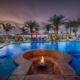 A serene pool surrounded by lounge chairs and a fire pit, creating a perfect ambiance for relaxation and enjoyment.