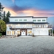 Photo of Modern two-story house at dusk with illuminated windows and a spacious driveway.