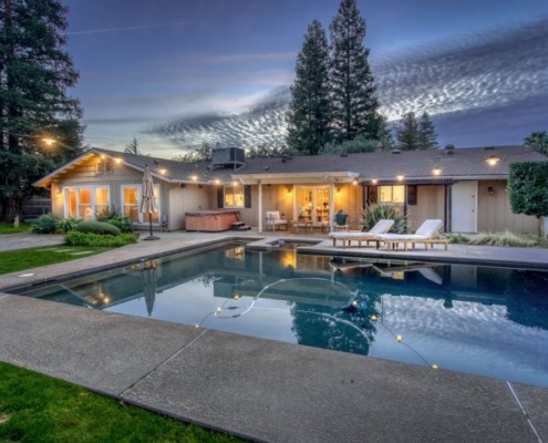 Photo of exterior view of evening lighting showing backyard with swimming pool and Jacuzzi