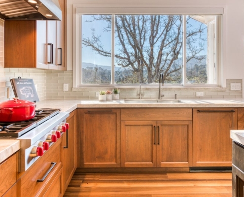A kitchen with wooden cabinets and a large window providing ample natural light.