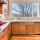 A kitchen with wooden cabinets and a large window providing ample natural light.