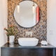 A bathroom with a black and white tile floor and a round mirror reflecting the elegant ambiance.